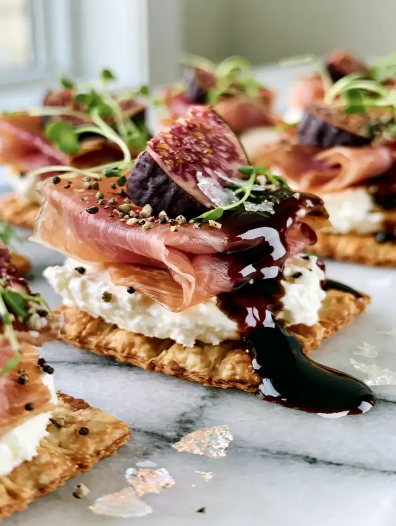 An elegant arrangement of no-cook new year's eve snacks featuring dark purple figs and micro-greens.