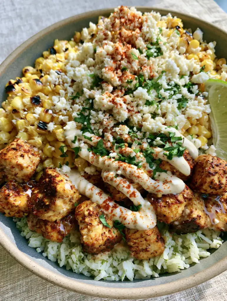 Street Corn Chicken Bowl assembled in a matte ceramic bowl with fresh lime wedge and cotija cheese.