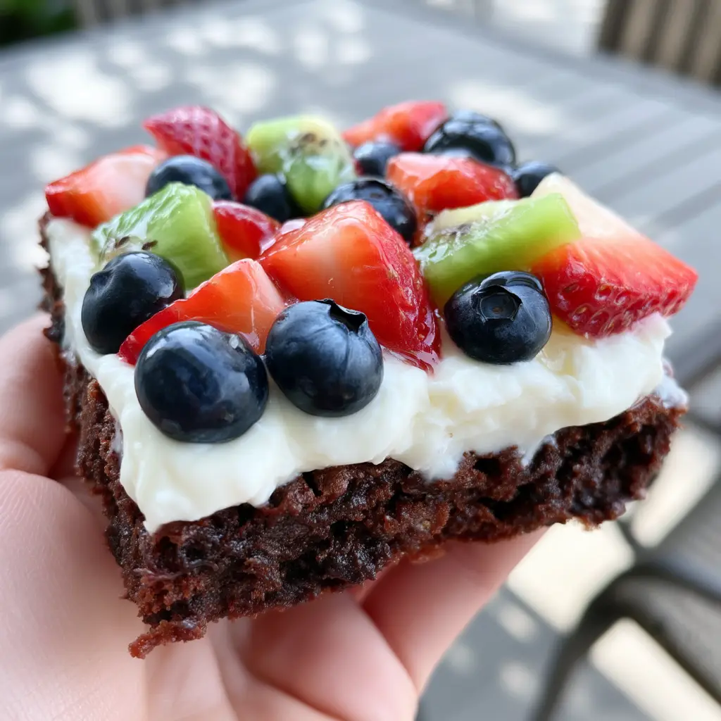 Close up of the velvety cream cheese frosting and glistening fruit on a brownie fruit pizza.