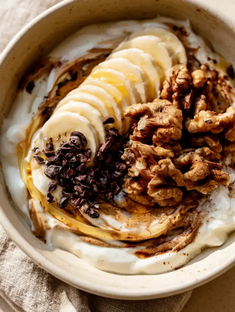 Midnight Snacks: The Ultimate Creamy Almond Butter and Greek Yogurt Bowl 1 Slices of banana and raw walnuts on top of a yogurt bowl, ideal for midnight snacks.