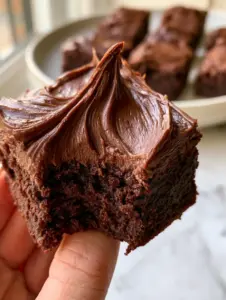 Macro close-up of a thick square lunch lady brownie with a bite taken out revealing a moist fudgy center.