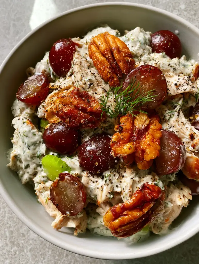 Professional smartphone photo of Chicken salad with toasted pecans and fresh dill garnish.