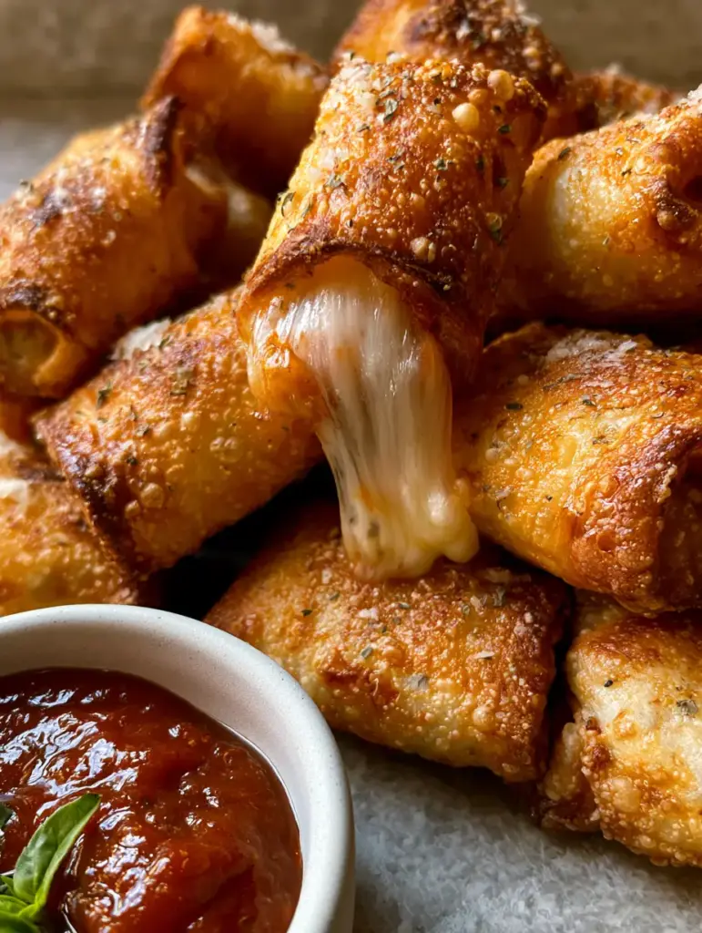 Air Fryer Pizza Rolls: The Ultimate Crispy Homemade Guide 2 Macro shot of golden-brown air fryer pizza rolls showing air bubbles, oregano specks, and a matte bowl of marinara. (air fryer pizza rolls)