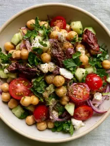 Close-up of golden chickpeas and ruby-red cherry tomatoes in a lemon-herb glaze. (chickpea salad)