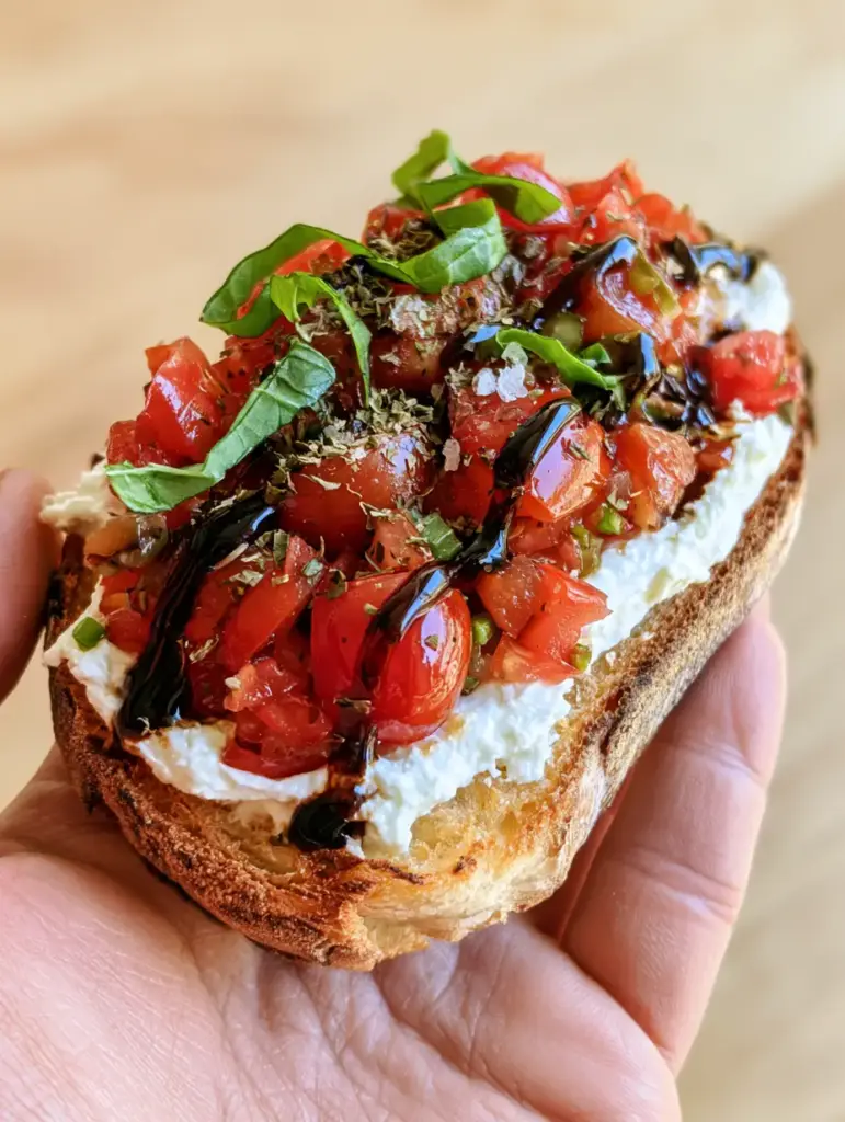 Greek Bruschetta with Whipped Feta and Balsamic Glaze 1 Side view of Greek Bruschetta showing the thick layer of cheese and mahogany balsamic glaze zig-zags.