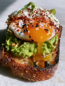 Close-up of toasted sourdough bubbles and chunky emerald avocado for a Breakfast sandwich with avocado.