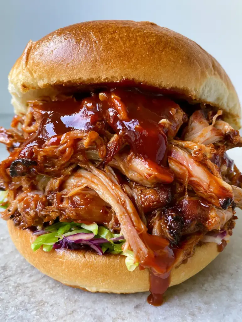 Instant Pot BBQ Pulled Pork with Glossy Hickory Sauce and Crisp Slaw 1 A side view of the BBQ pulled pork sandwich showing the layers of purple slaw and micro-thin pickles.
