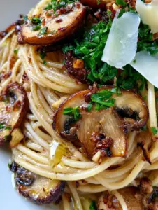 Macro close-up of glossy al dente strands in a Mushroom and Garlic Spaghetti dish with bright green parsley and toasted garlic bits.