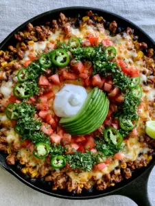 Sizzling ground turkey taco meat in a black skillet with charred corn and black beans. (Ground Turkey Taco Skillet)